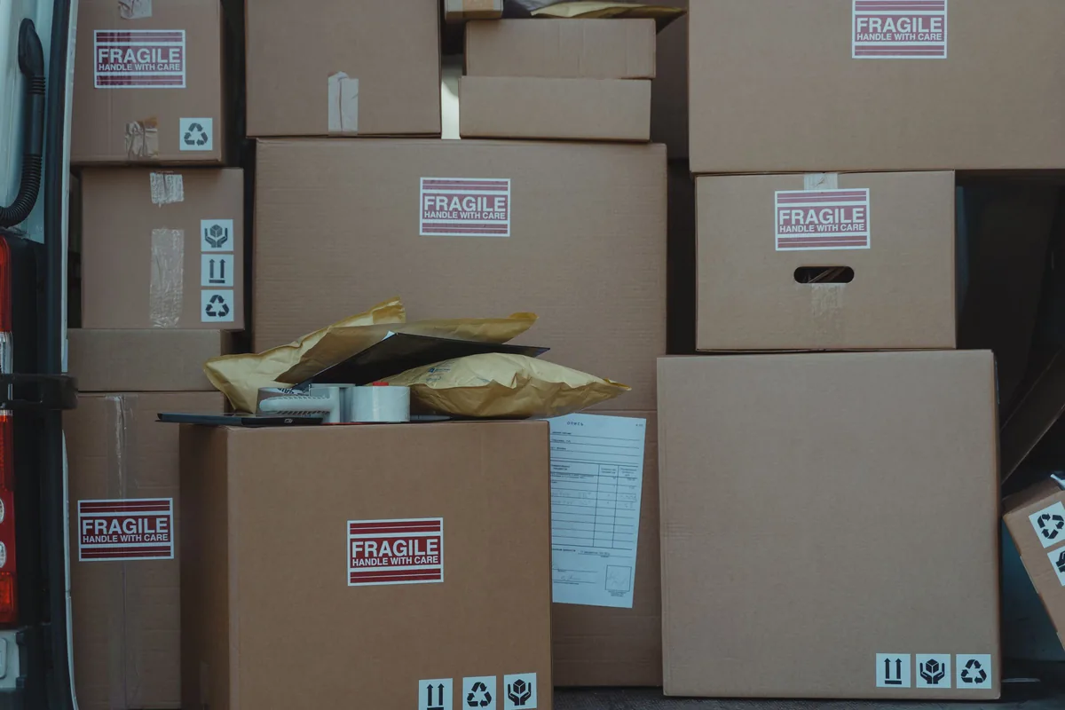 Cardboard shipping boxes with handling labels stacked inside a delivery vehicle.